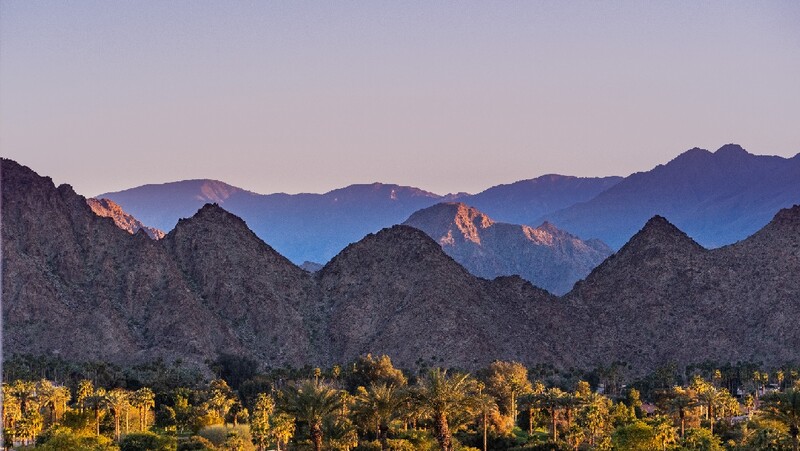 View of mountain, sky and the tops of palm trees in Palm Desert, CA. Stock Photo