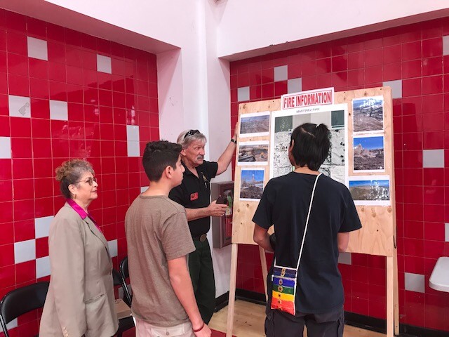 Four people look at a visual display depicting mulch fires in Thermal, at a school gym in 2019.