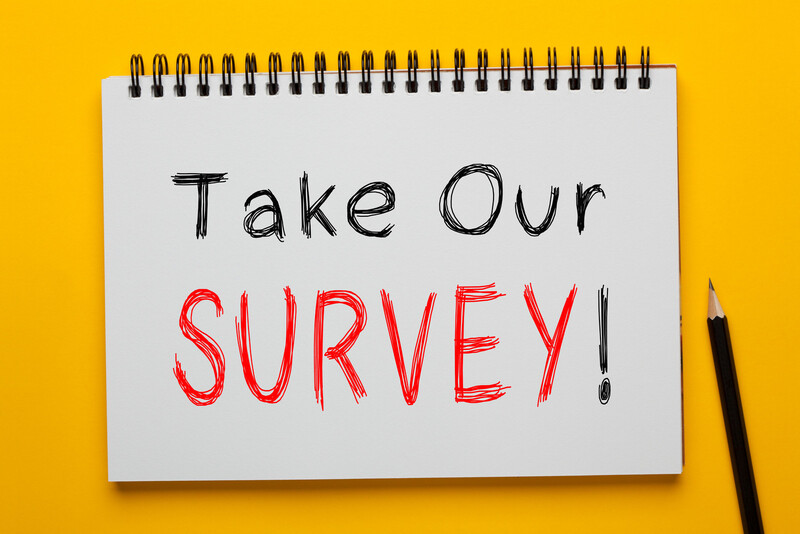 "Take Our Survey" is printed in black and red letters on a white tablet with a pencil nearby and a  bright yellow background.