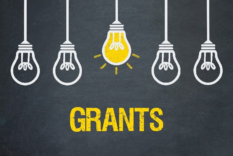 Five lightbulbs hanging from the ceiling; the background is dark gray with "Grants" in bright yellow. The middle bulb is on.