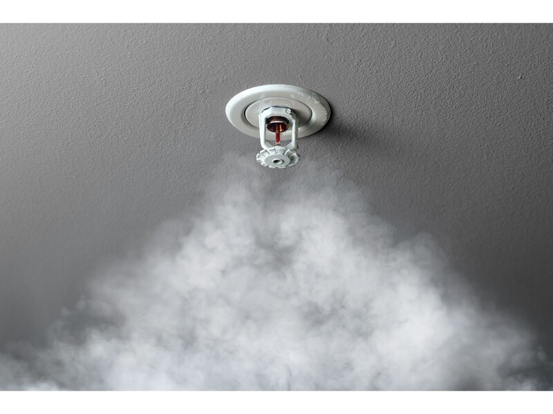 Fire Sprinkler installed in a ceiling with smoke drifting up toward it.
