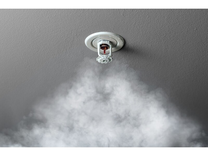 A fire sprinkler detects smoke. Stock Photo Fire Sprinkler installed in a ceiling with smoke drifting up toward it.
