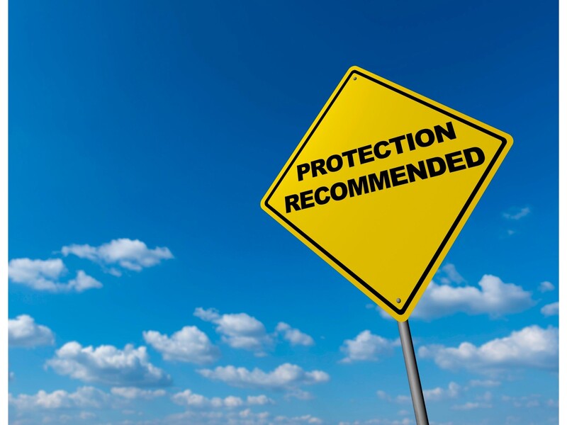 A yellow road sign with "Protection Recommended" in black letters with a blue sky and minimal clouds as the background.