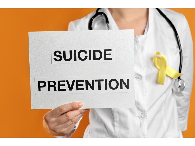 Medical professional in white coat holds a sign that reads "Suicide Prevention." Stock Photo