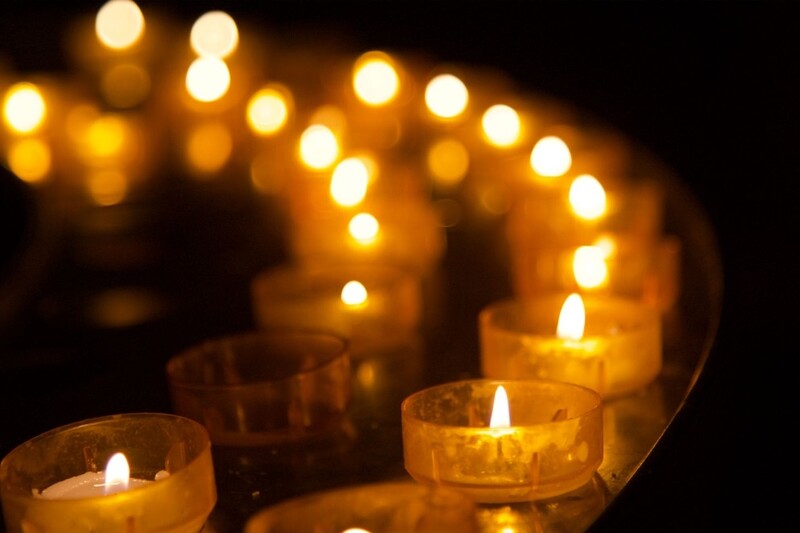 Two rows of flaming votive candles at night. Stock Photo