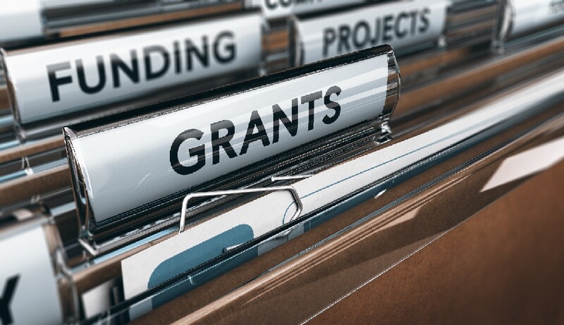 A row of file folders with the prominent folder labelled "Grants." Stock Photo
