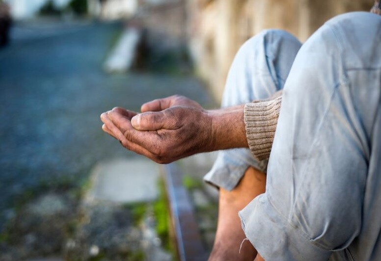 Cupped soiled hands of an unsheltered person sitting on the ground. Stock Photo
