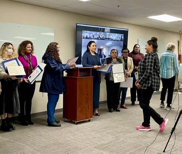 A member of CVEC approaches a podium where two women stand to hand out certificates of appreciation. Photo by District Staff