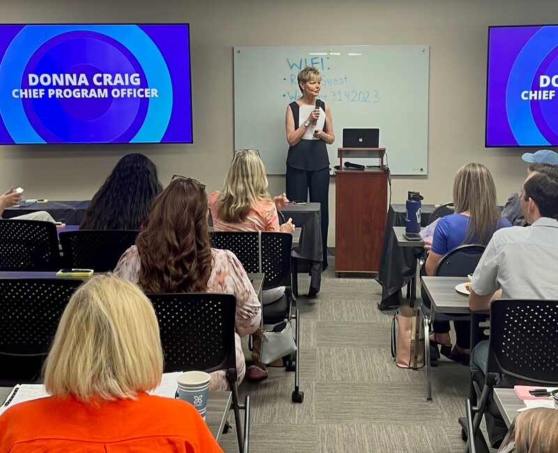 Chief Program Officer Donna Craig addresses participants at a data walk in support of the Desert Healthcare District and Foundation's environmental health initiative. Photo by Will Dean Donna Craig with microphone in hand faces a seated audience during the 2024 data walk.
