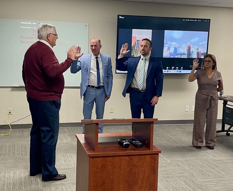 Desert Healthcare District & Foundation attorney Jeff Scott swears in four Board Directors, one of whom is participating via Zoom. Staff Photo Attorney Jeff Scott stands with a raised hand facing three Board Directors who also have raised their right hands, in a conference room.