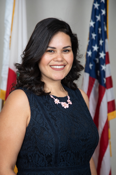 DHCD Board Director Karen Borja smiling with U.S. and California state flags in background