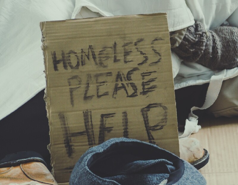 Homeless sign next to a makeshift bed where someone sleeps